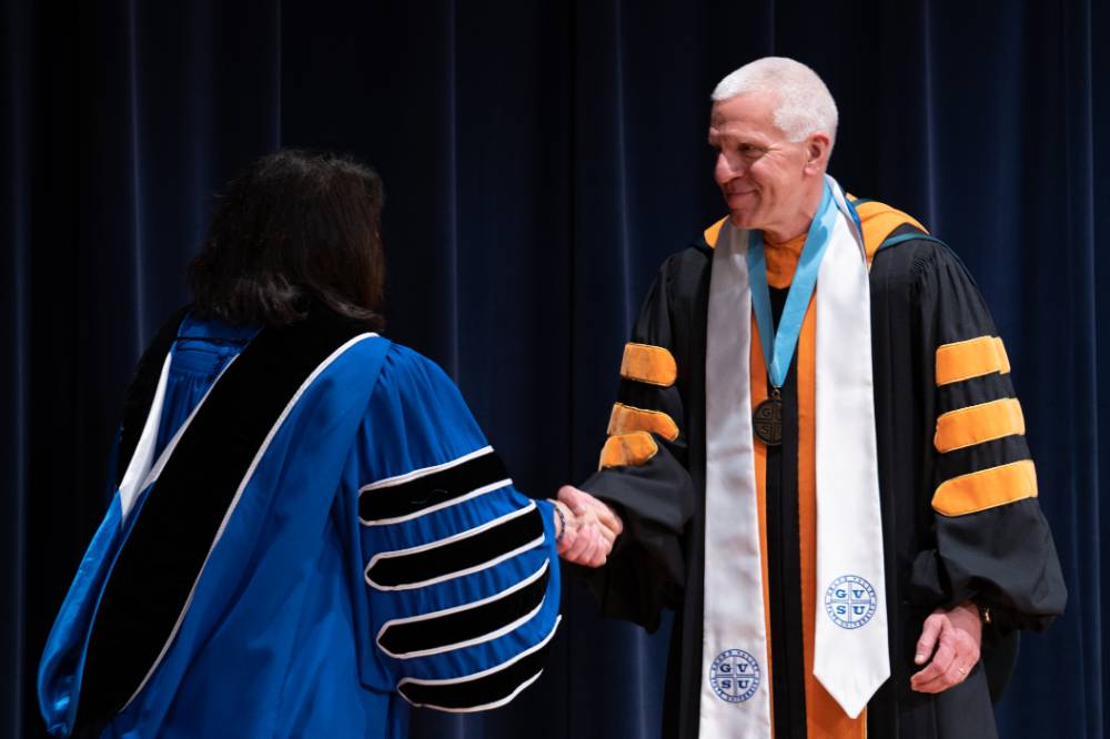President and Faculty member shaking hands on stage
